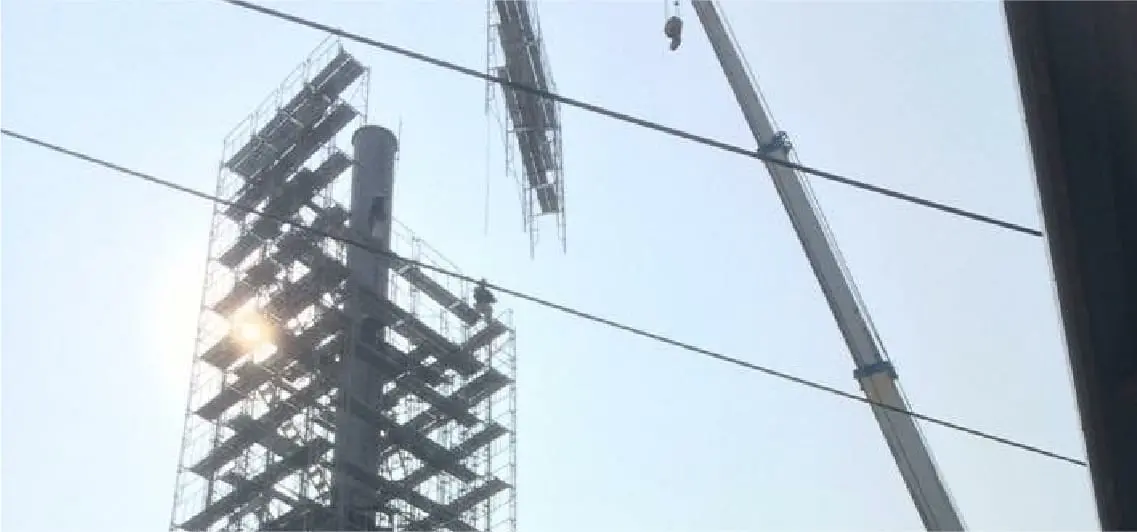 足場が組まれた高い建物とクレーン、青空を背景にした建築工事の様子