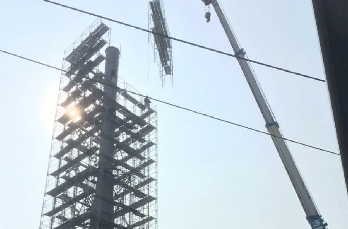 太陽光を背景に建設中の高層鉄骨構造物