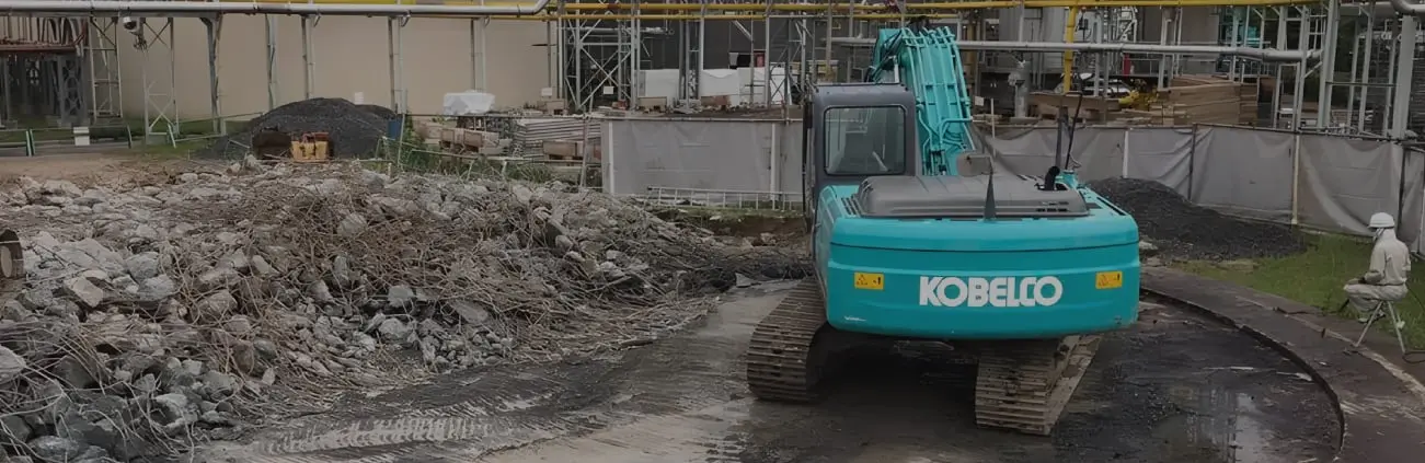 緑色の重機が土を掘削している土木工事現場