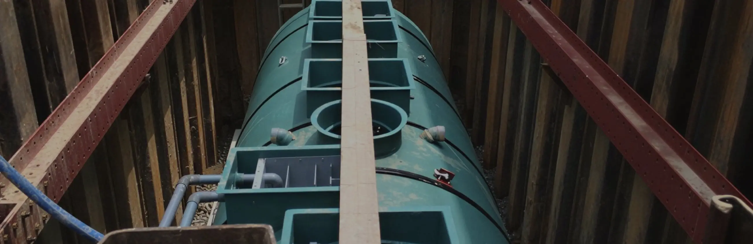 緑色の円筒形浄化槽が地中に設置されている工事現場