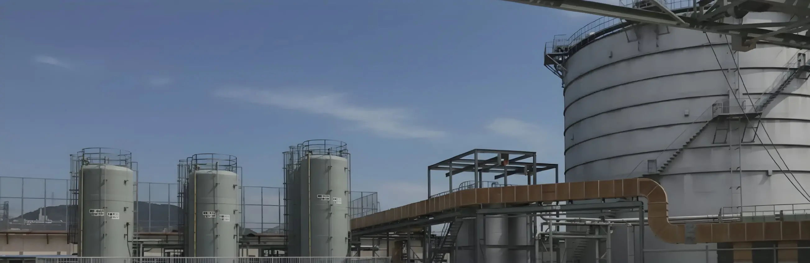 白い円筒形タンクと配管設備が並ぶ水処理プラント施設の全景